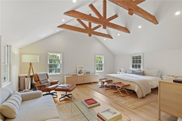 bedroom with beam ceiling, light wood-type flooring, and high vaulted ceiling