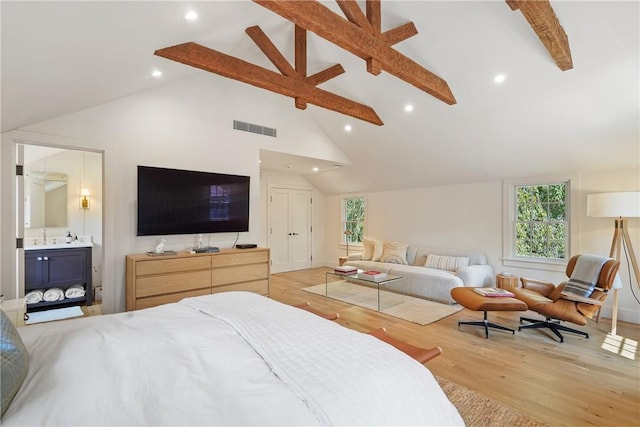 bedroom with beam ceiling, light wood-type flooring, high vaulted ceiling, and ensuite bath