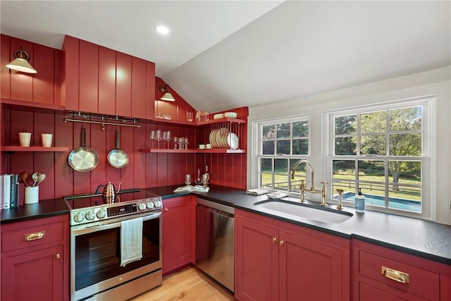 kitchen with appliances with stainless steel finishes, light hardwood / wood-style floors, vaulted ceiling, and sink