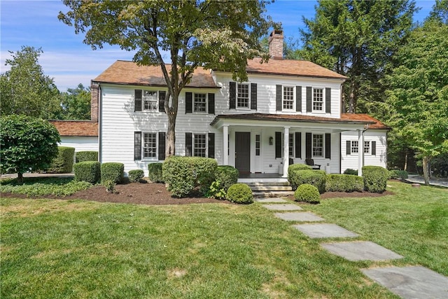 colonial-style house featuring a porch and a front lawn