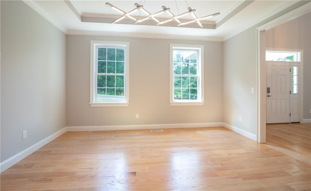 foyer entrance with light wood-type flooring, ornamental molding, and a tray ceiling