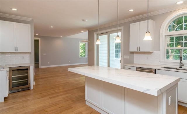 kitchen featuring decorative backsplash, a kitchen island, white cabinetry, and light hardwood / wood-style flooring