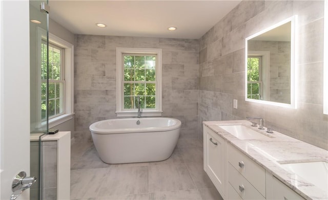 bathroom with vanity, tile walls, and a tub