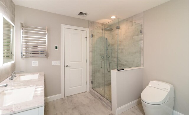 bathroom with radiator heating unit, vanity, and a shower with shower door