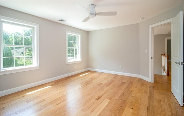 empty room featuring ceiling fan, plenty of natural light, and light wood-type flooring