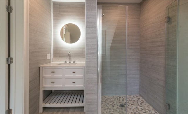 bathroom with vanity, tile walls, and walk in shower