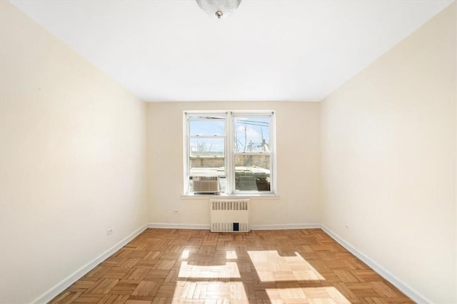 empty room with radiator heating unit, light parquet flooring, and cooling unit