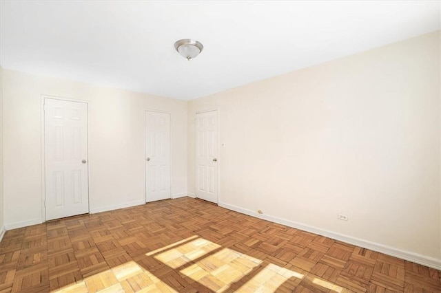 unfurnished bedroom featuring multiple closets and light parquet flooring