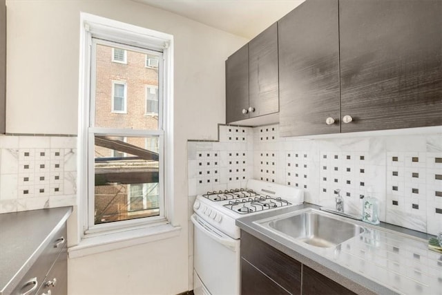 kitchen featuring decorative backsplash, dark brown cabinetry, gas range gas stove, and sink