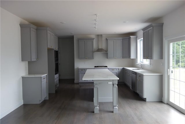 kitchen featuring wall chimney exhaust hood, gray cabinets, and a kitchen island