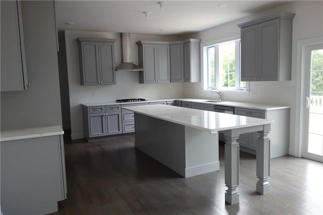 kitchen featuring wall chimney exhaust hood, gray cabinets, plenty of natural light, and stainless steel gas cooktop