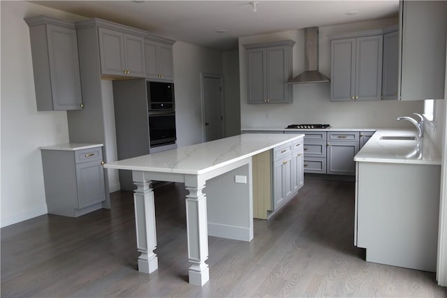 kitchen featuring wall chimney exhaust hood, sink, wood-type flooring, a center island, and gray cabinets