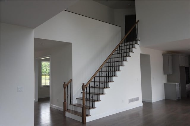 stairway featuring hardwood / wood-style flooring and a towering ceiling