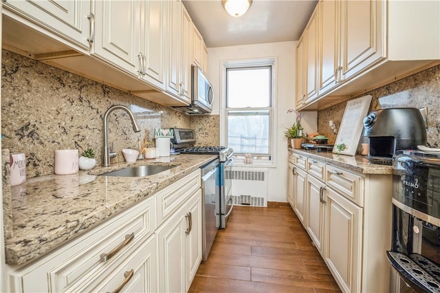 kitchen featuring sink, decorative backsplash, light wood-type flooring, light stone counters, and stainless steel appliances