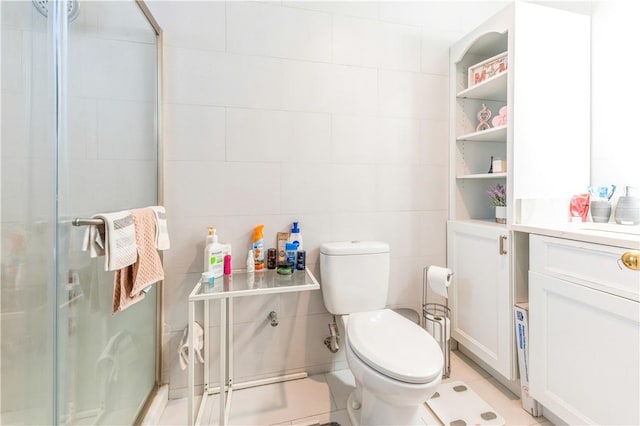 bathroom with vanity, tile patterned floors, toilet, tile walls, and a shower with shower door