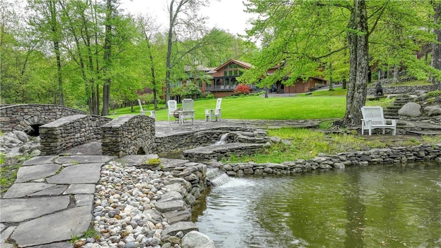 view of home's community featuring a lawn and a water view