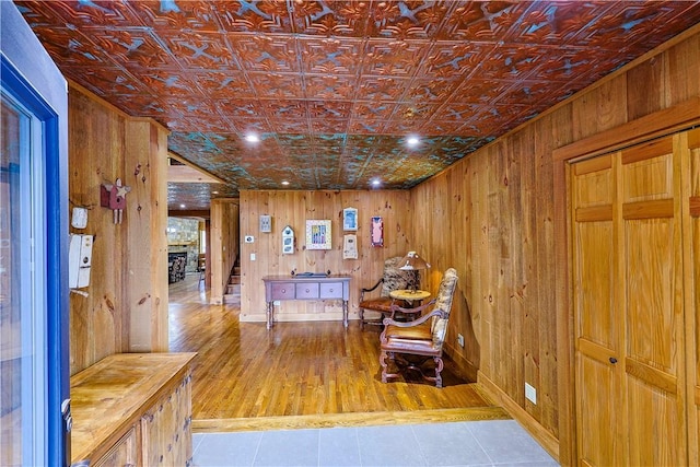 corridor featuring light wood-type flooring and wood walls