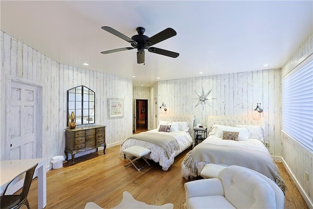 bedroom featuring ceiling fan, hardwood / wood-style floors, and wooden walls