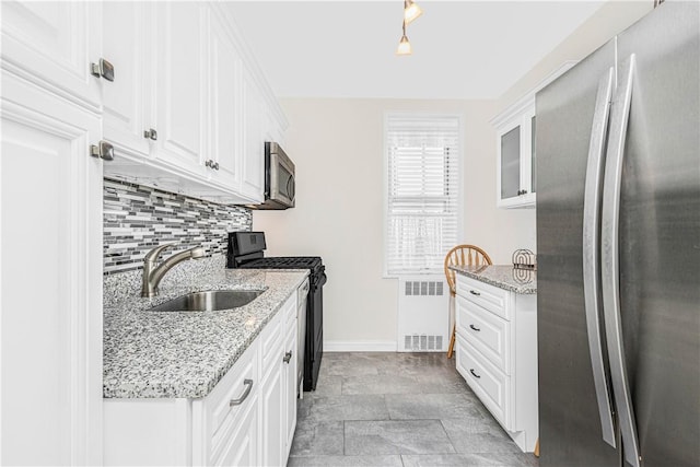 kitchen featuring appliances with stainless steel finishes, white cabinetry, radiator, and sink