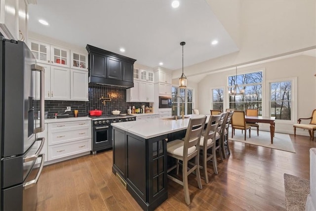 kitchen featuring hanging light fixtures, a center island with sink, stainless steel appliances, and wood-type flooring