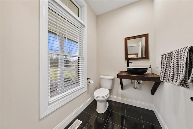 bathroom with toilet, sink, and tile patterned flooring