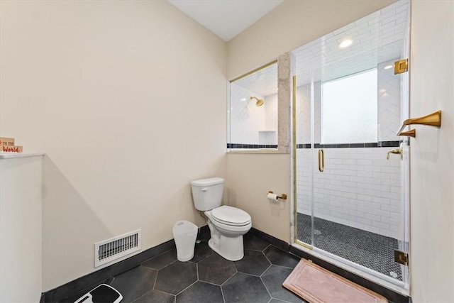 bathroom featuring tile patterned flooring, toilet, and an enclosed shower