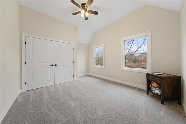 unfurnished bedroom featuring ceiling fan, a closet, light carpet, and vaulted ceiling