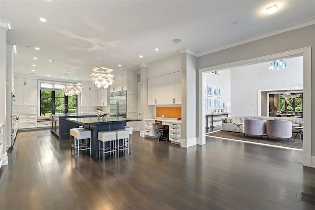 kitchen featuring white cabinetry, tasteful backsplash, dark hardwood / wood-style floors, stainless steel built in refrigerator, and an island with sink