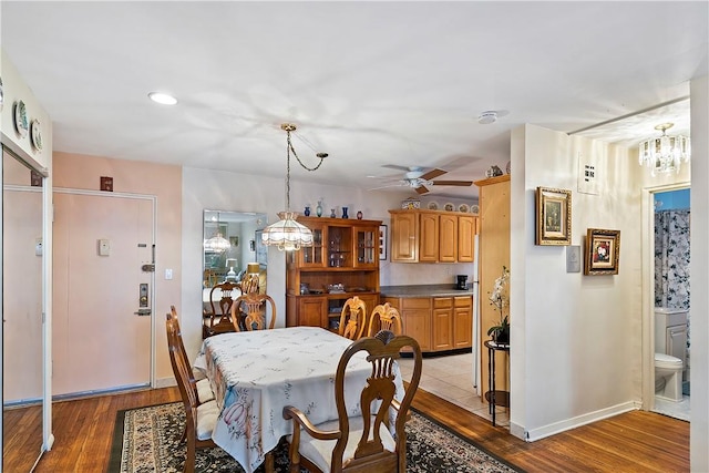 dining room with ceiling fan with notable chandelier and light wood-type flooring