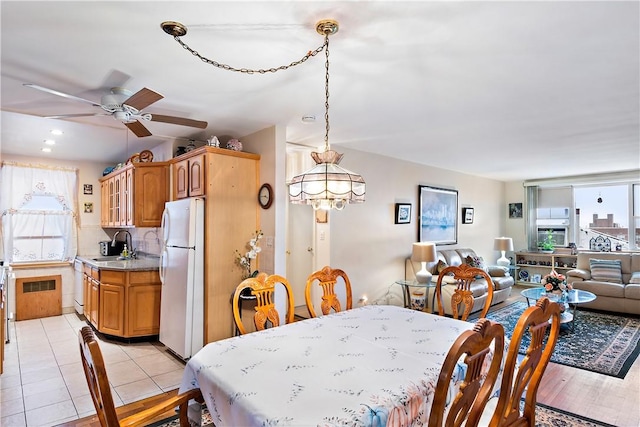 dining area featuring sink, ceiling fan with notable chandelier, and light wood-type flooring