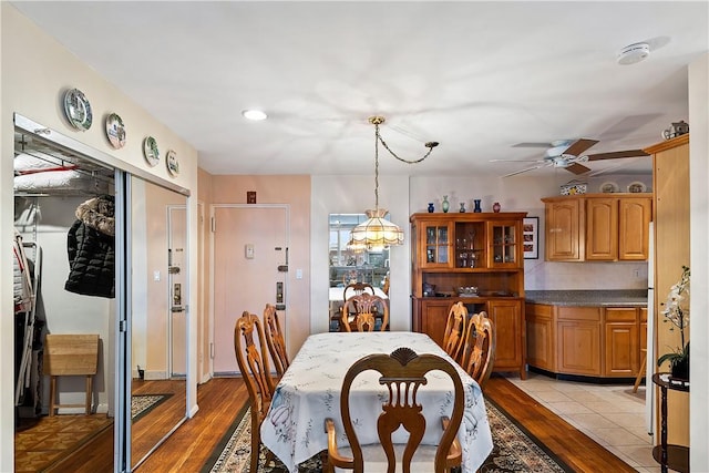 dining space featuring light hardwood / wood-style floors and ceiling fan with notable chandelier