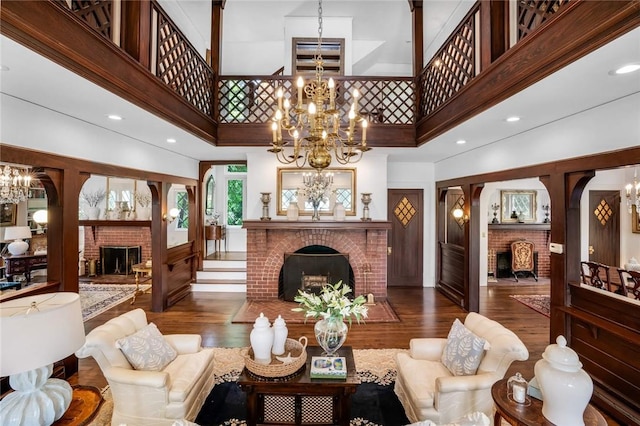 living room with dark hardwood / wood-style flooring, a towering ceiling, and a brick fireplace