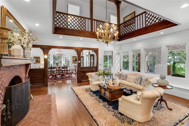 living room with a chandelier, a fireplace, hardwood / wood-style floors, and a high ceiling