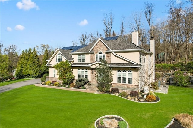 view of front facade with a front yard and solar panels