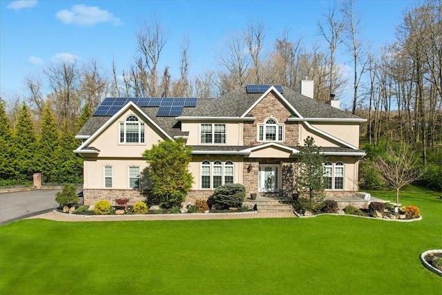 view of front of property featuring solar panels and a front lawn