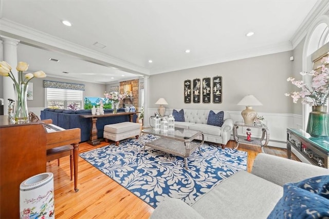 living room with ornate columns, crown molding, and hardwood / wood-style floors