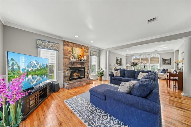 living room featuring ornamental molding, a fireplace, a wealth of natural light, and light hardwood / wood-style flooring