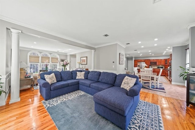 living room with light hardwood / wood-style floors, ornamental molding, and decorative columns