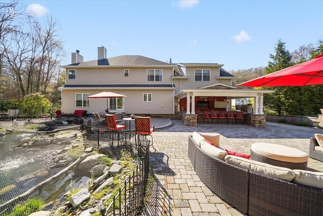 rear view of property with an outdoor hangout area, an outdoor bar, and a patio area