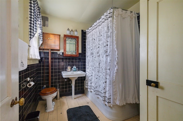 full bathroom featuring sink, toilet, tile walls, and shower / tub combo