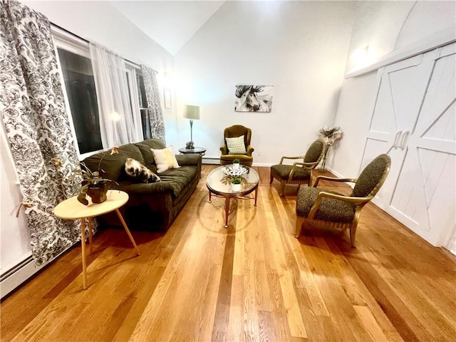 sitting room featuring hardwood / wood-style floors, a baseboard radiator, and lofted ceiling