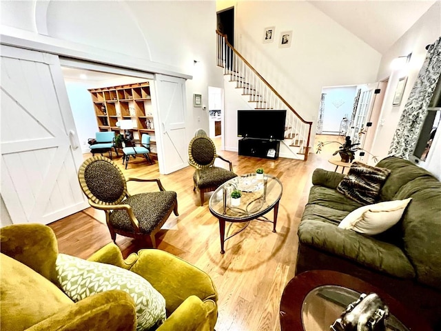 living room featuring high vaulted ceiling and light hardwood / wood-style flooring