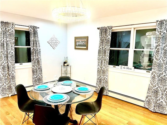 dining area featuring wood-type flooring and a baseboard heating unit