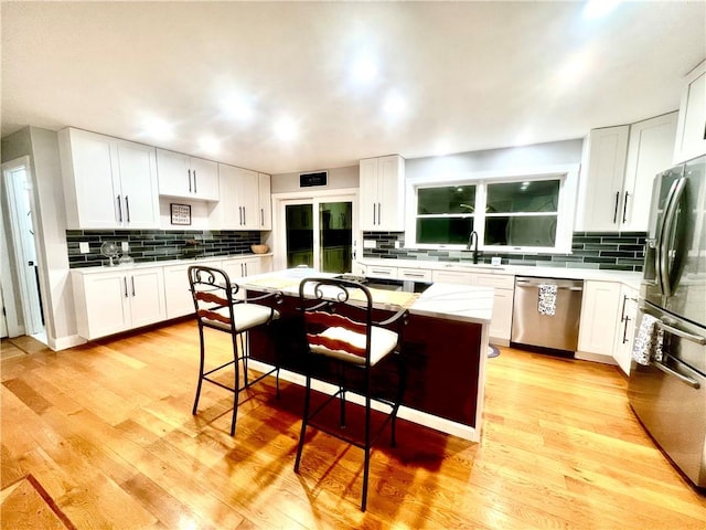 kitchen featuring white cabinets, a breakfast bar, a kitchen island, and appliances with stainless steel finishes