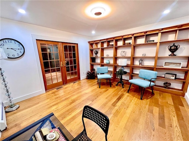 living area with french doors and light hardwood / wood-style flooring