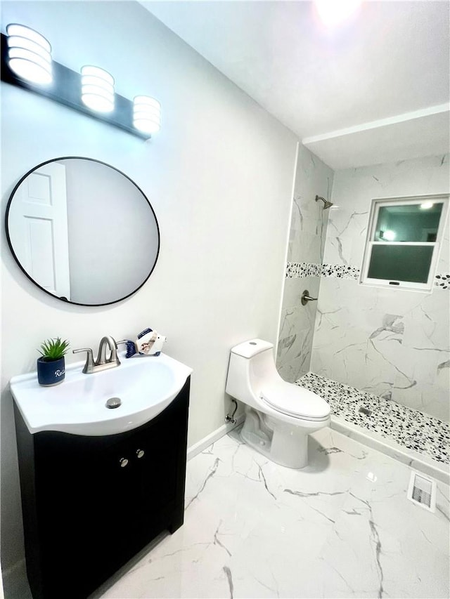 bathroom featuring a tile shower, vanity, and toilet