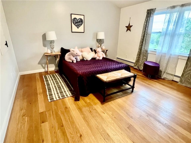 bedroom with hardwood / wood-style floors and a baseboard heating unit