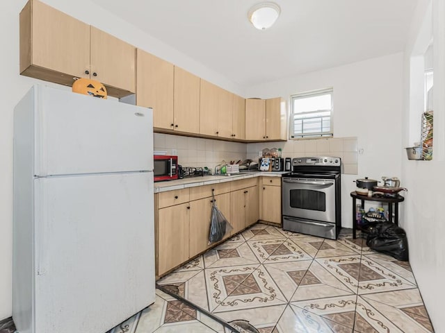 kitchen with light brown cabinets, stainless steel range with electric cooktop, white refrigerator, decorative backsplash, and light tile patterned floors