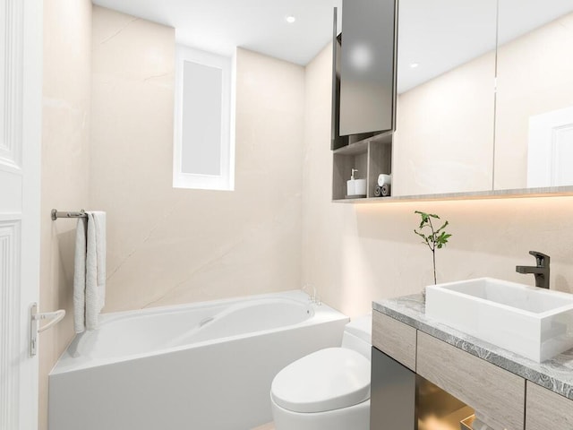 bathroom with a washtub, vanity, and toilet