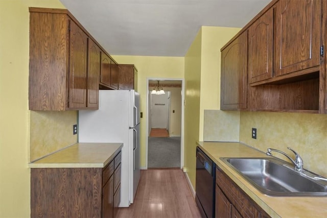 kitchen with dark wood-type flooring, sink, a chandelier, black dishwasher, and white fridge